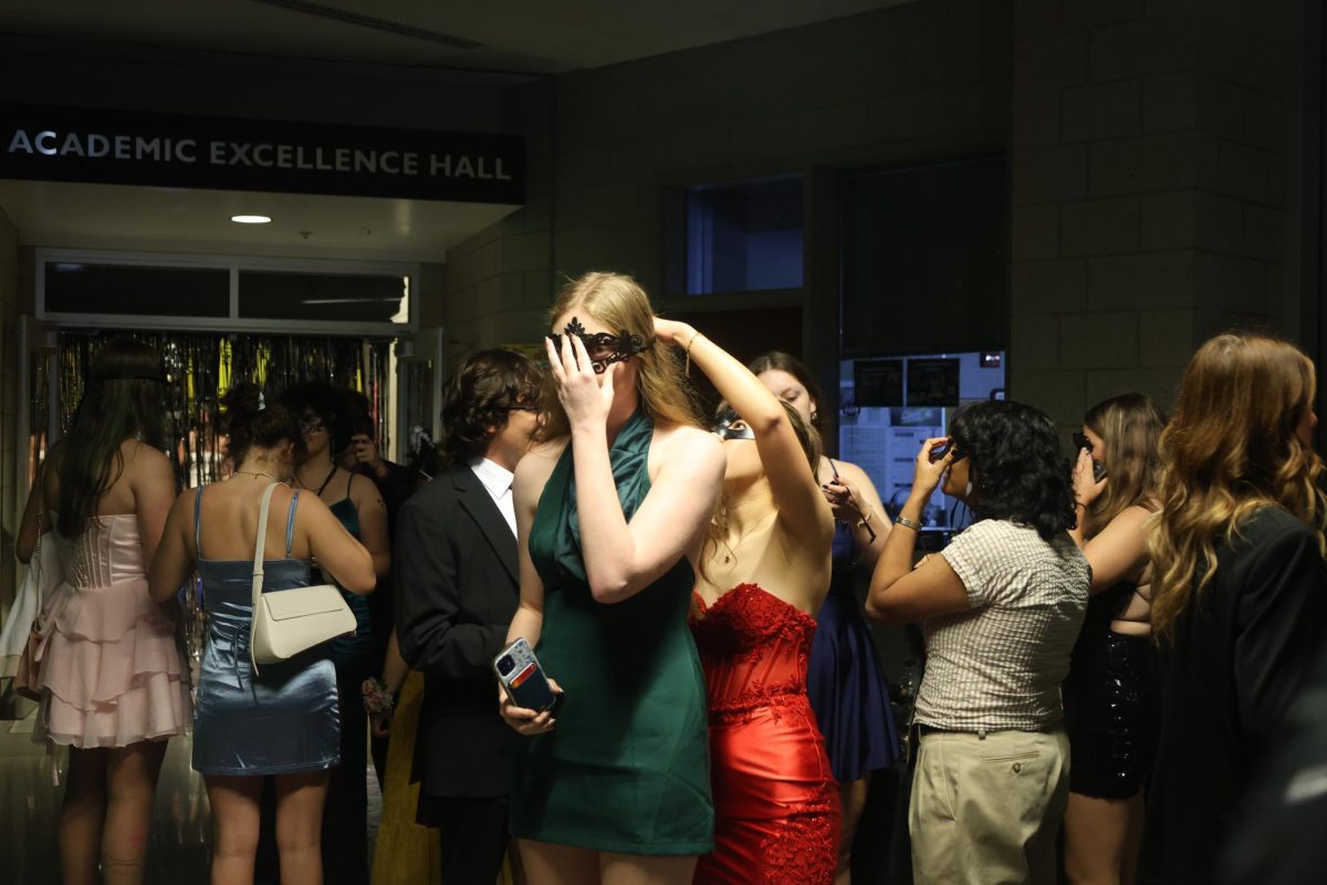 Dressed to the theme, senior Sophia	Manczuk helps senior Theresa Korte tie her mask for the Homecoming dance on Oct. 25.