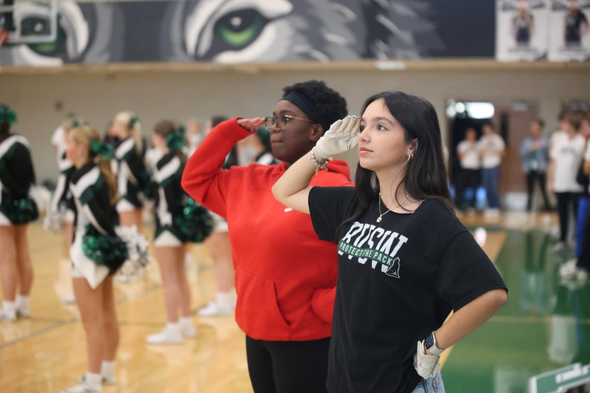 In the national anthem, senior Anna Munyenze and junior Bella Borrell salute during the winter assembly on Dec. 4.