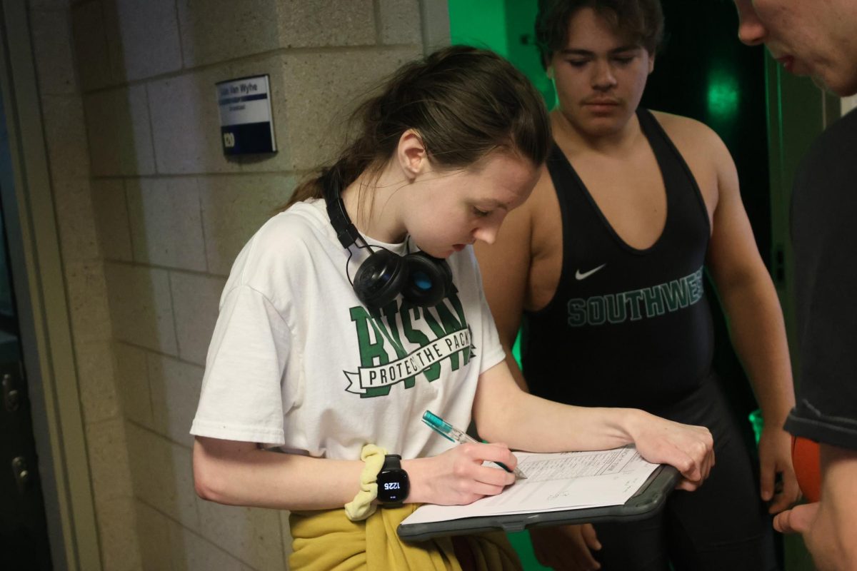 Taking roll, senior Faith Mazurier writes the names for the boys wrestling team during media day on Dec. 2.