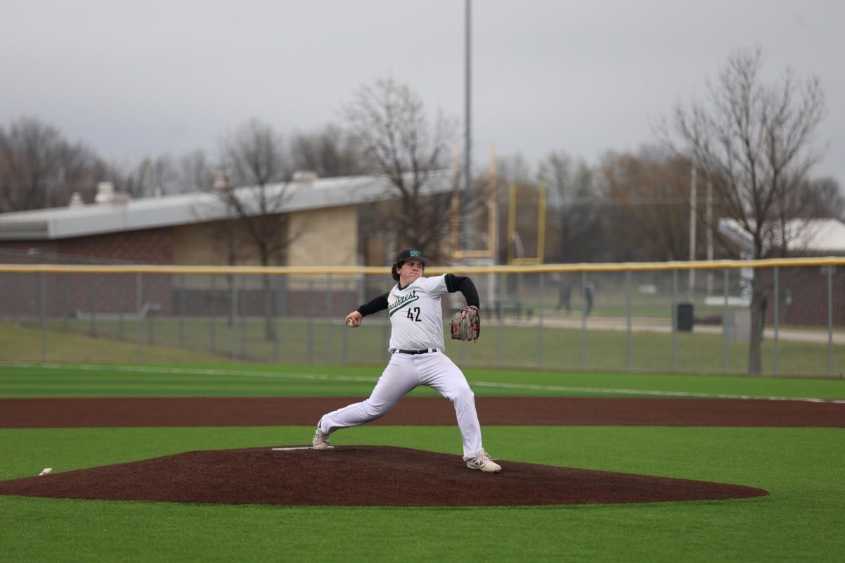 Mid-throw, sophomore Silus Huckaby pitches on the mound during their game against Aquinas on April 1. The Timberwolves fell short with a final score of 3-7. 
