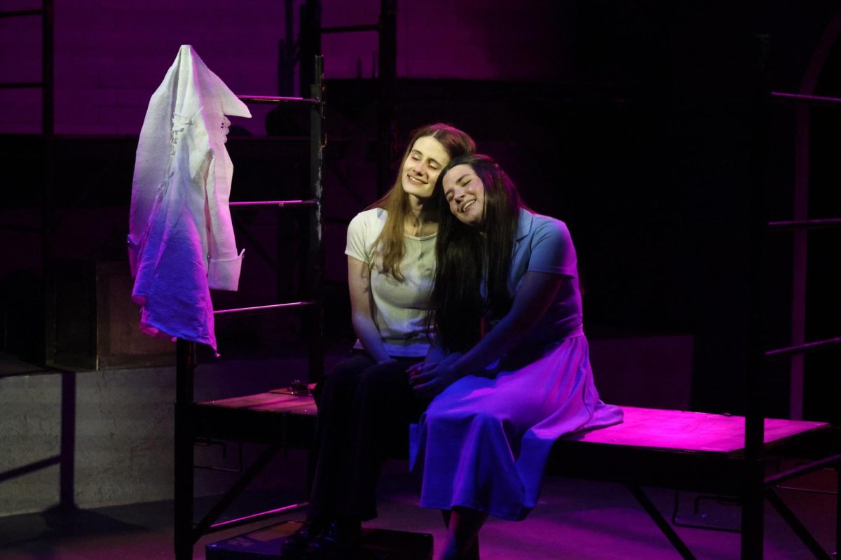 Head on shoulder, senior Madeline Hendricks and junior Juna Finks lean up against each other at the “Alice by Heart" dress rehearsal on April 15.