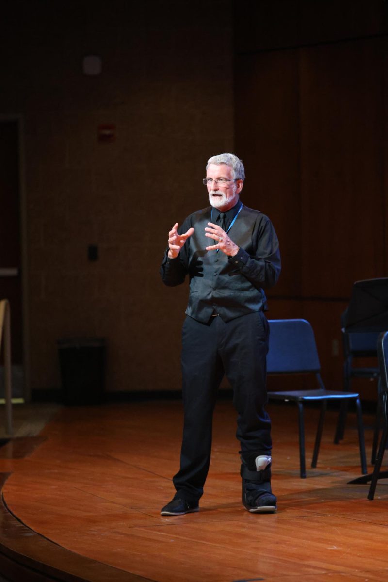 On stage, orchestra teacher Lewis Bullock introduces the next piece the students will perform on May 5. 