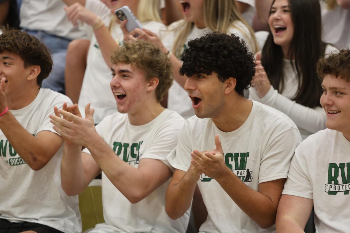 Smile on face, senior Amir Yazdanparast cheers on his classmates during the prom assembly on April 23.
