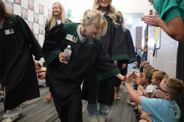 Smile on her face, senior Delaney Wills high-fives the elementary school students lining the halls during the Timber Creek walk through on May 14.