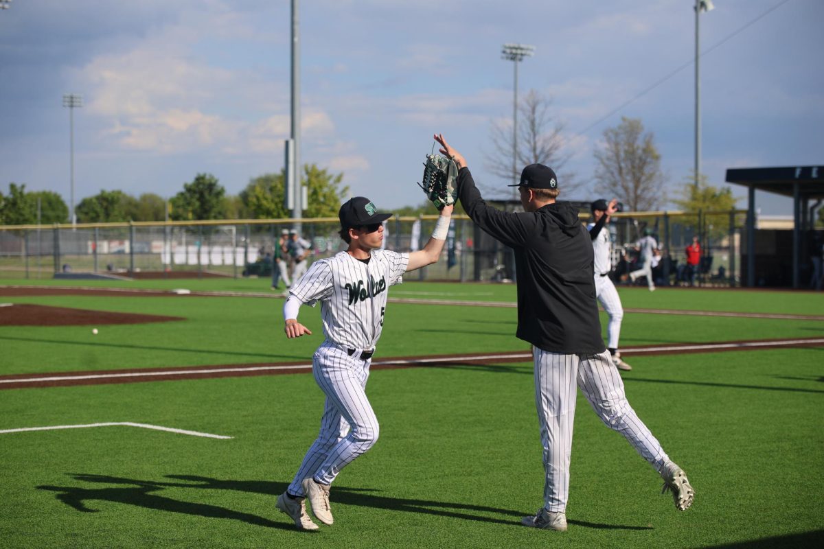 Arm high, senior Jackson Blume high-fives his teammate during their game against De Soto on May 1.