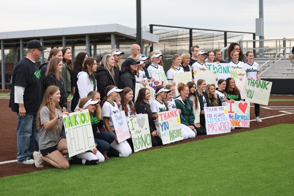 Full of smiles, the softball team poses for a group photo with the staff members they chose to showcase in honor of teacher appreciation week on May 5. The team created posters to carry as they walked out with each teacher.